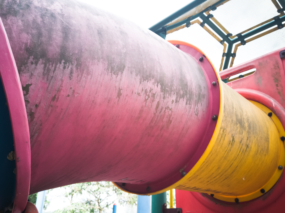 A dirty, enclosed playground slide that needs a deep cleaning