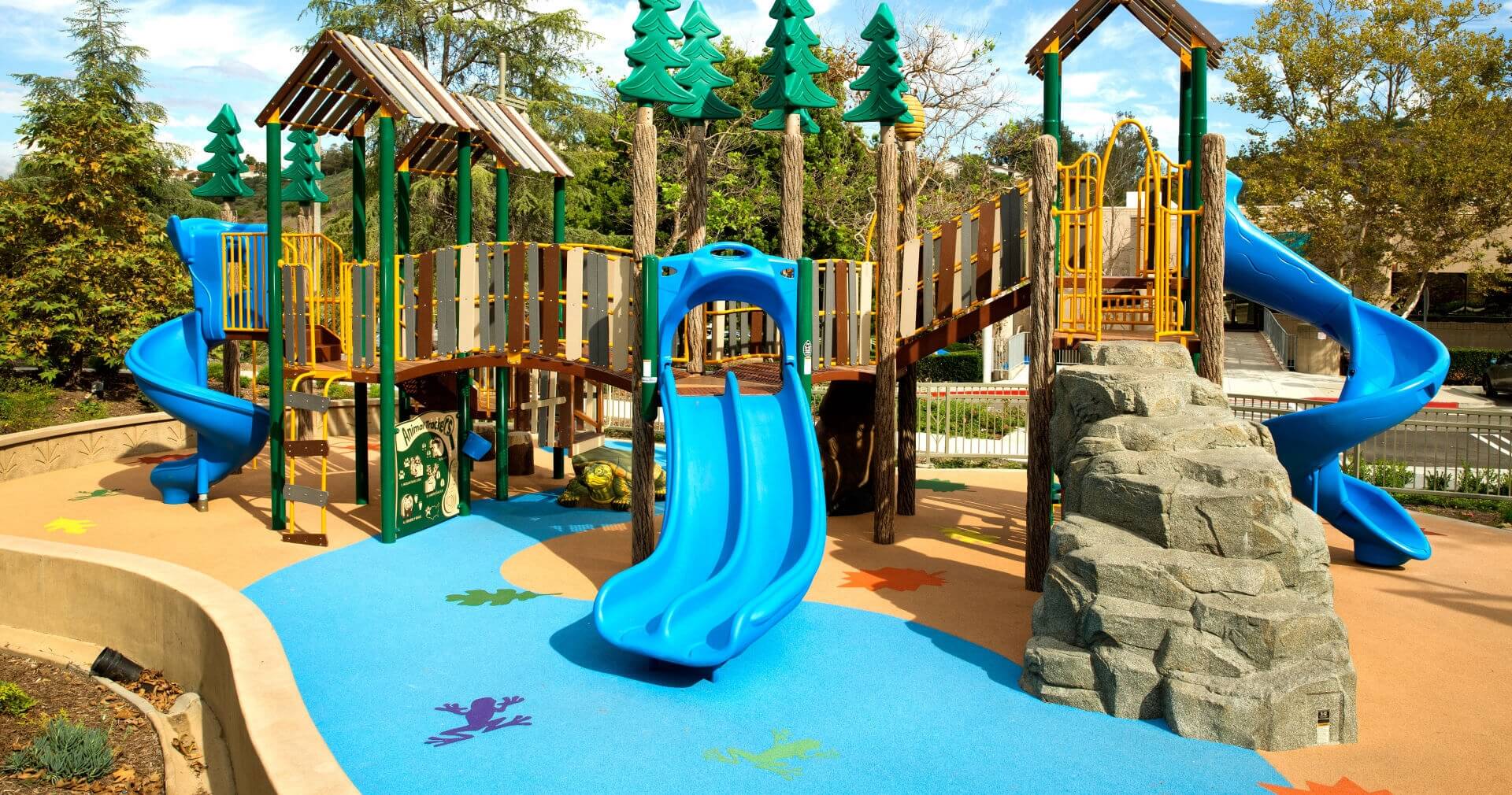 A playground with a poured rubber surface with frog graphics.